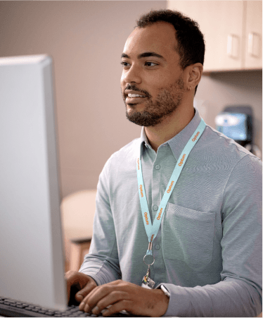 Professional man in an office wearing an ID badge, working on a computer.